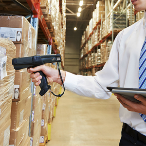 man in tie holding tablet and scanner, scanning boxes in warehouse