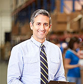 man with tie in warehouse holding clipboard