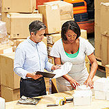 man and woman in warehouse packing boxes and checking off list