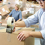 man and woman in warehouse packing boxes and taping them shut