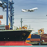 plane flying out of port over container ship
