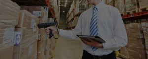 business man holding tablet and scanner, scanning boxes in warehouse
