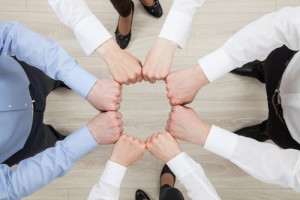 people in circle holding closed hands together to form circle