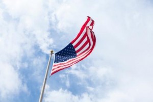 American flag flying in the wind with clouds in sky