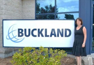 Therese Van Es standing with Buckland sign