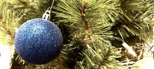 blue glittery ornament on christmas tree with lights