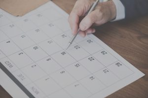 Hand with pen pointing to blank calendar