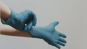 Blue latex gloves on hands against grey background