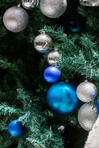 blue and silver ornaments hanging in greenery